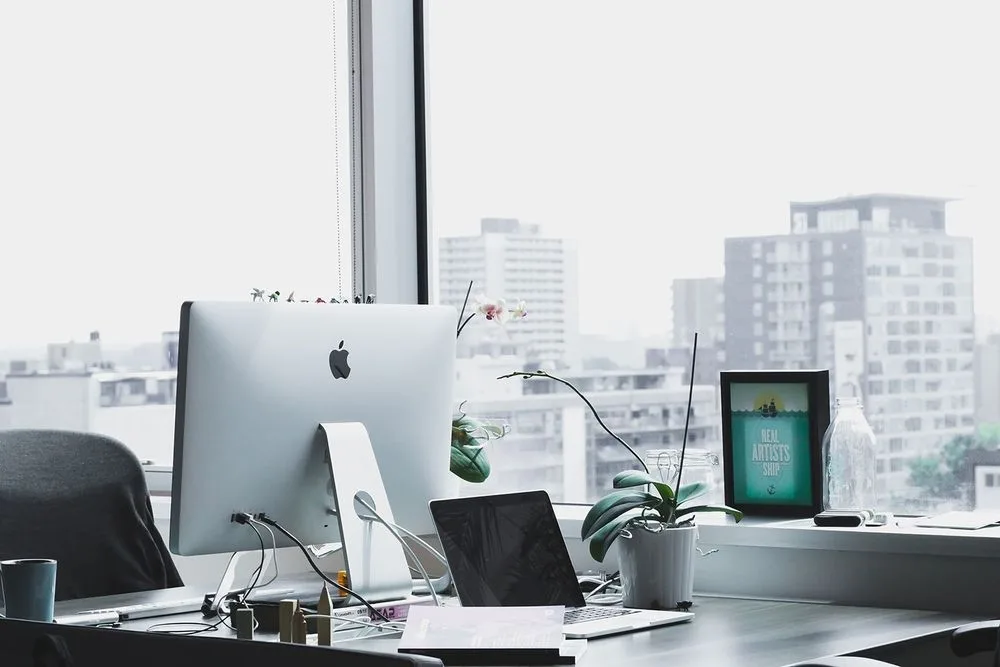 A bright office desk beside floor-to-ceiling windows